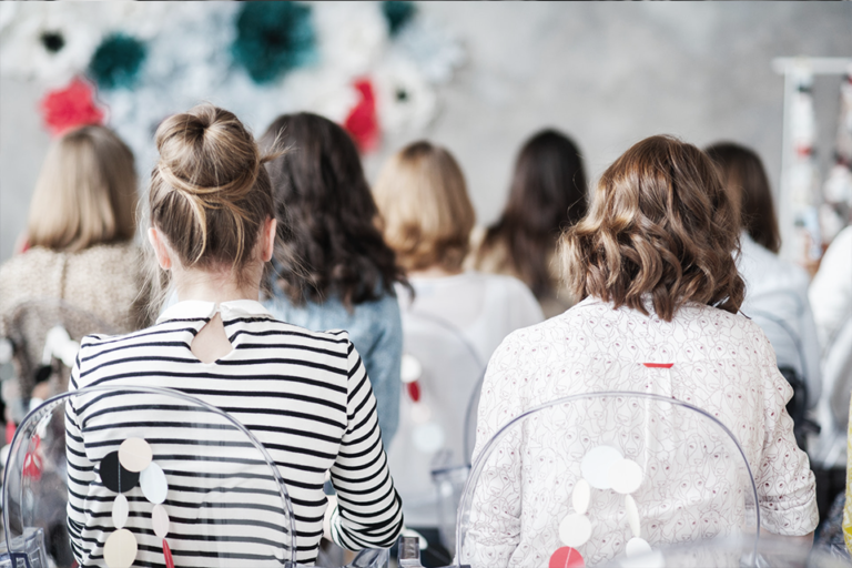 Mujeres de espaldas entre el público de un evento