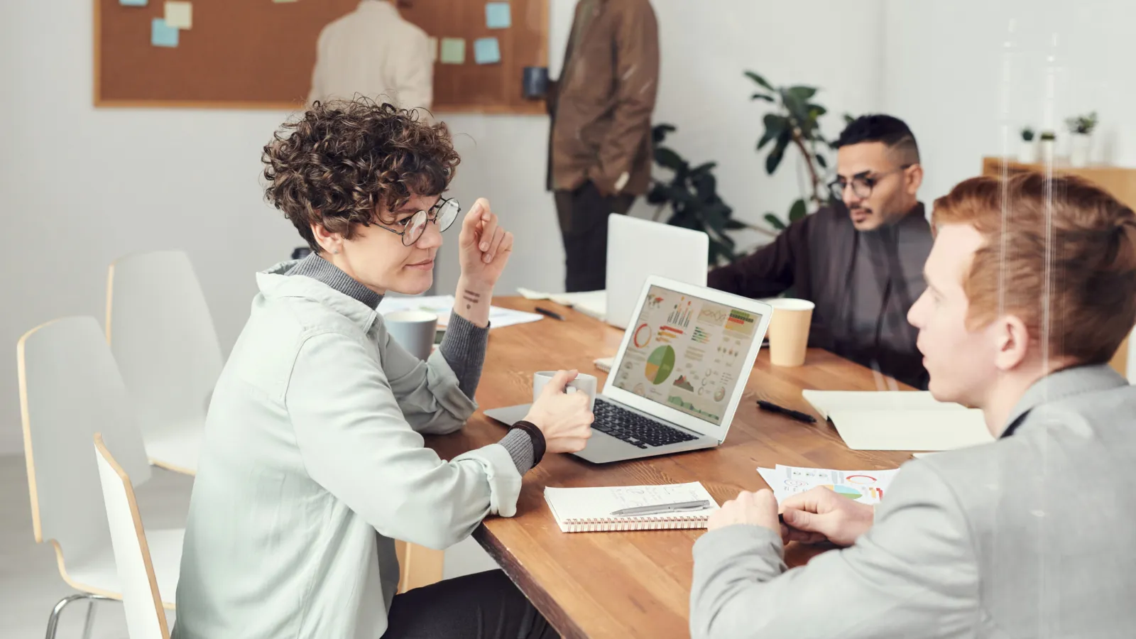 Equipo conversando alrededor de una mesa con una laptop que muestra gráficos