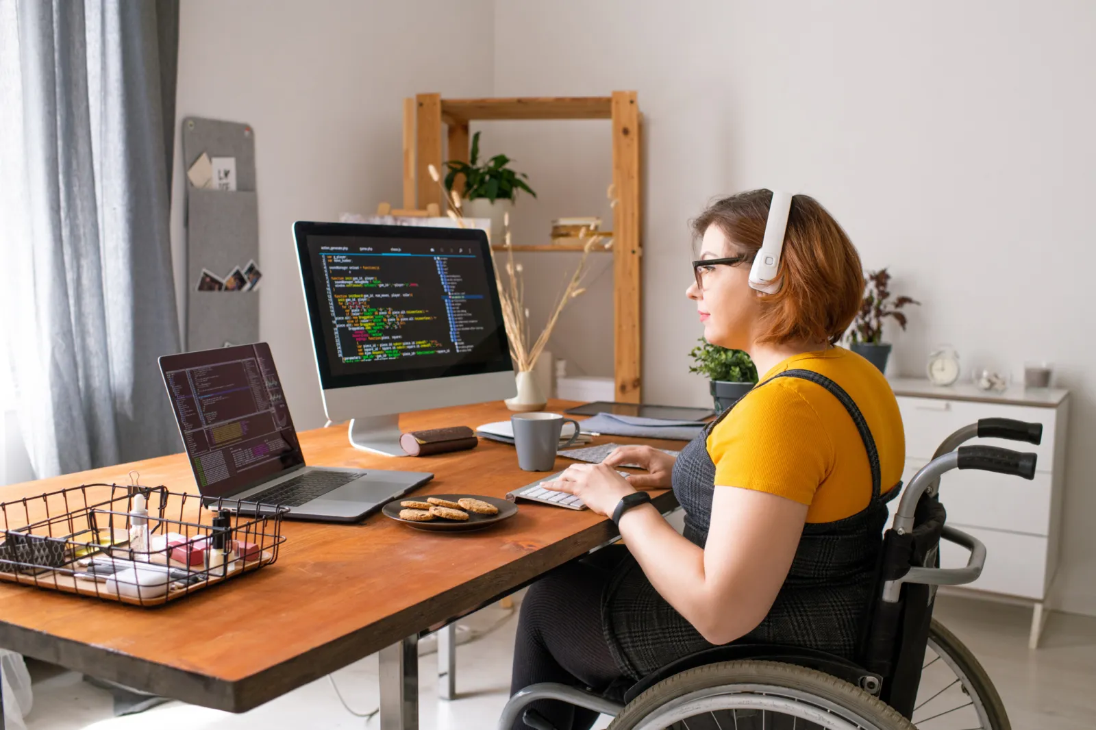 Mujer en silla de ruedas trabajando en su escritorio con dos pantallas