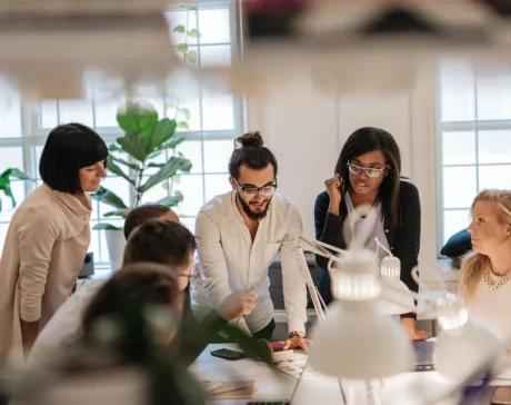 Equipo directivo reunido alrededor de una mesa de trabajo en una oficina luminosa