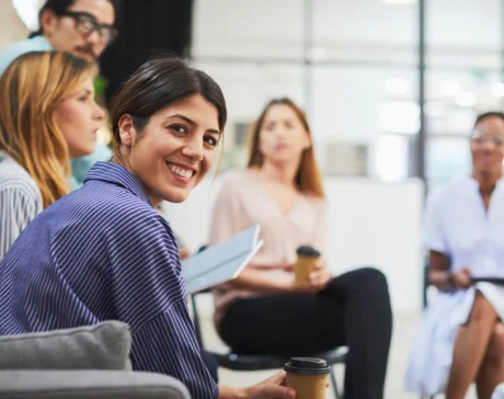Mujer sonriente en una reunión de equipo sentada en ronda